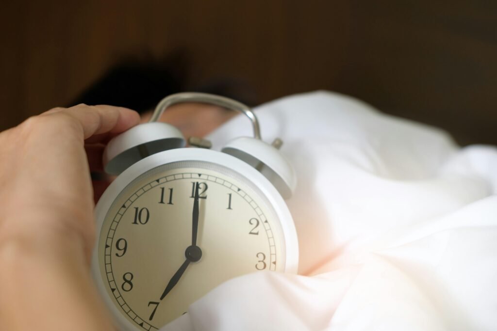 pexels-photo-1028741-1028741 A close-up of a hand reaching for a ringing alarm clock, symbolizing waking up in the morning.